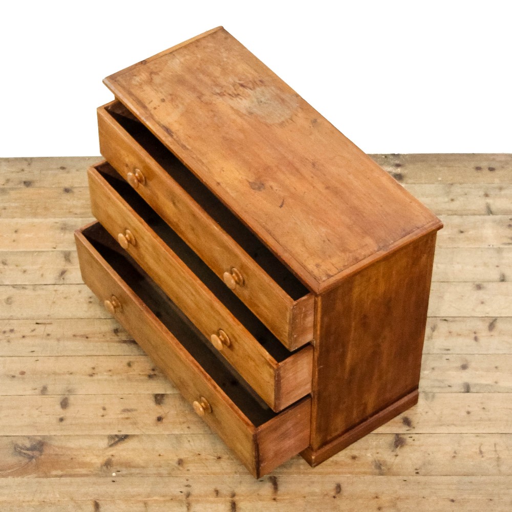 An antique pine chest of drawers featuring three wide drawers with turned wooden knob handles and a low plinth base. View VI