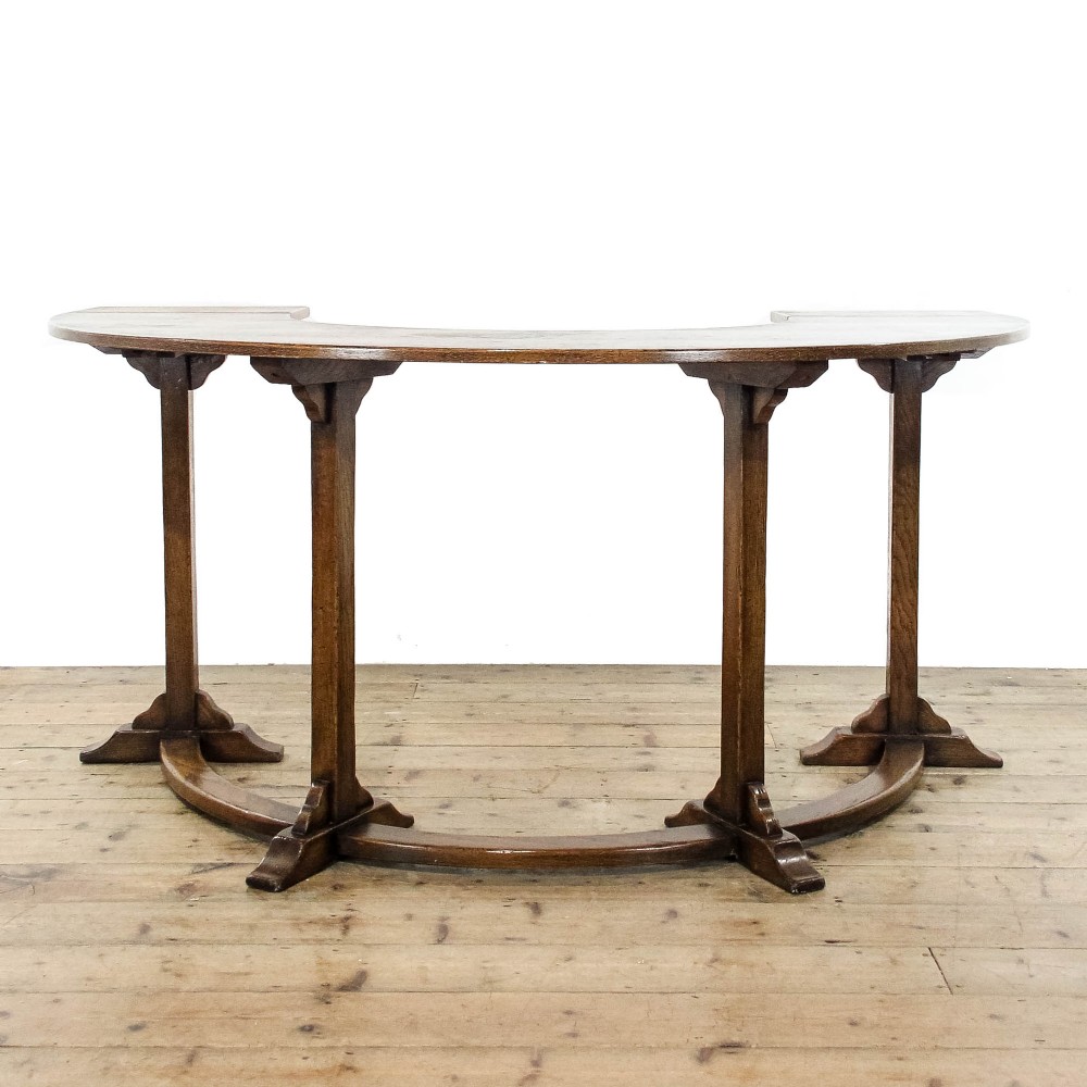 An antique dark oak horseshoe-shaped hunt table featuring upright trestle supports and a curved base stretcher.