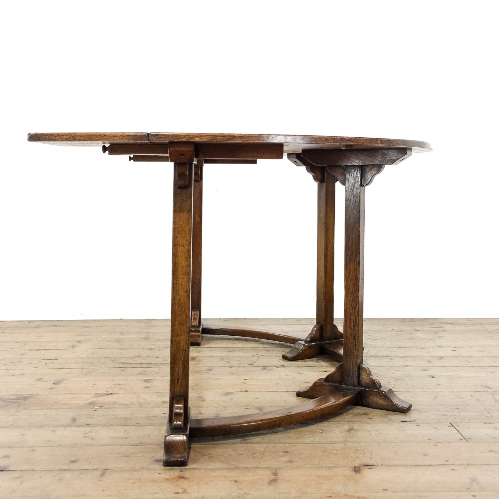 An antique dark oak horseshoe-shaped hunt table featuring upright trestle supports and a curved base stretcher. View III