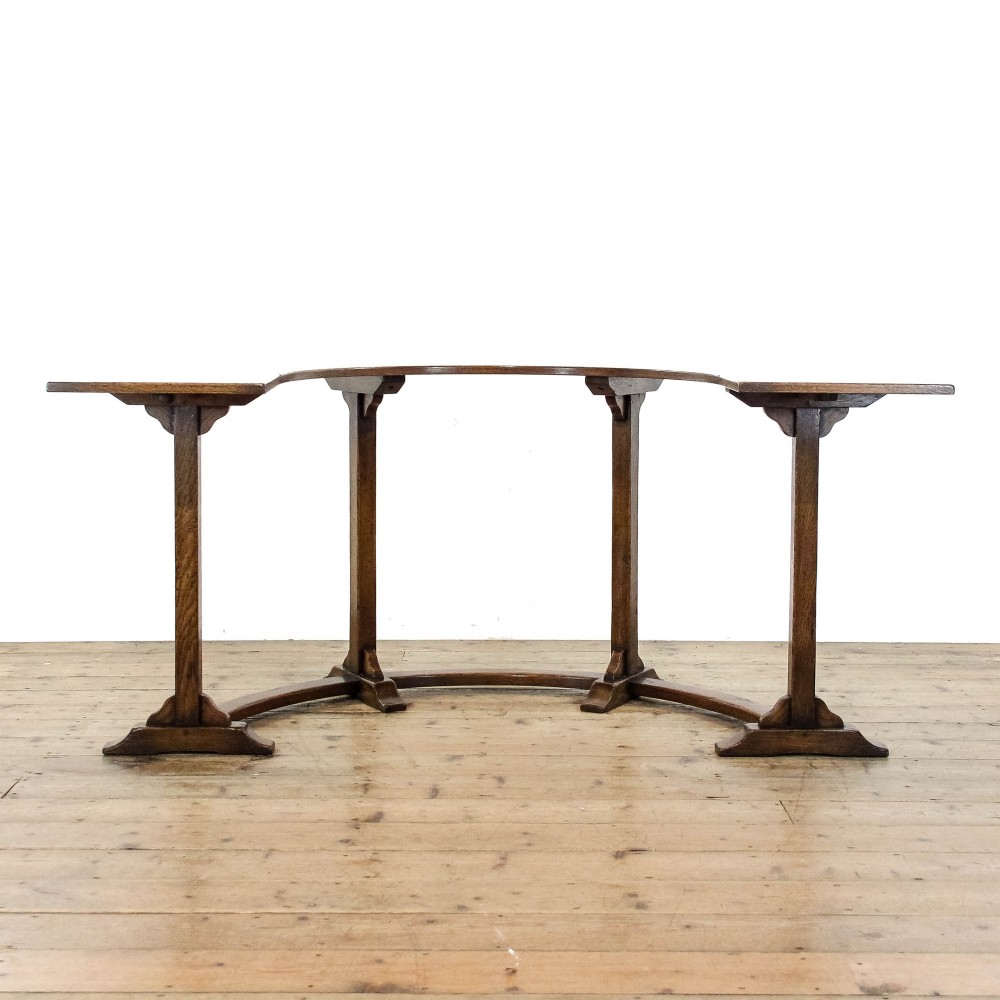 An antique dark oak horseshoe-shaped hunt table featuring upright trestle supports and a curved base stretcher. View IV