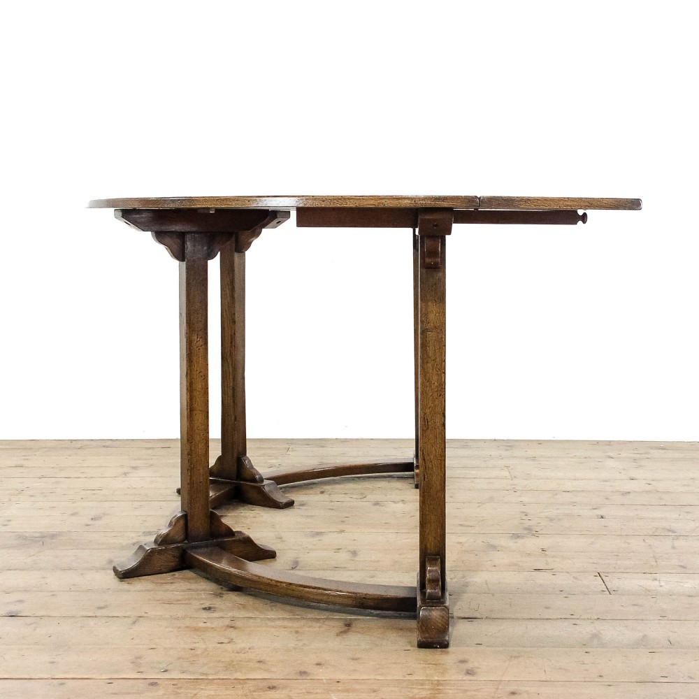 An antique dark oak horseshoe-shaped hunt table featuring upright trestle supports and a curved base stretcher. View V