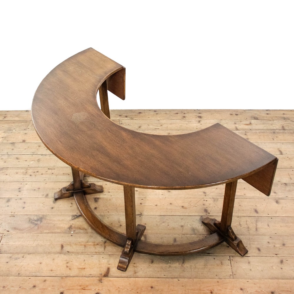 An antique dark oak horseshoe-shaped hunt table featuring upright trestle supports and a curved base stretcher. View VII