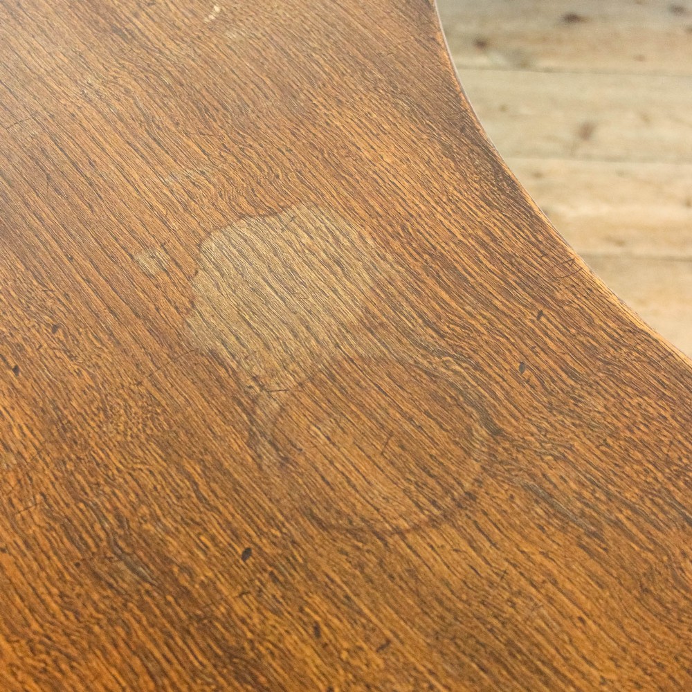 An antique dark oak horseshoe-shaped hunt table featuring upright trestle supports and a curved base stretcher. View IX