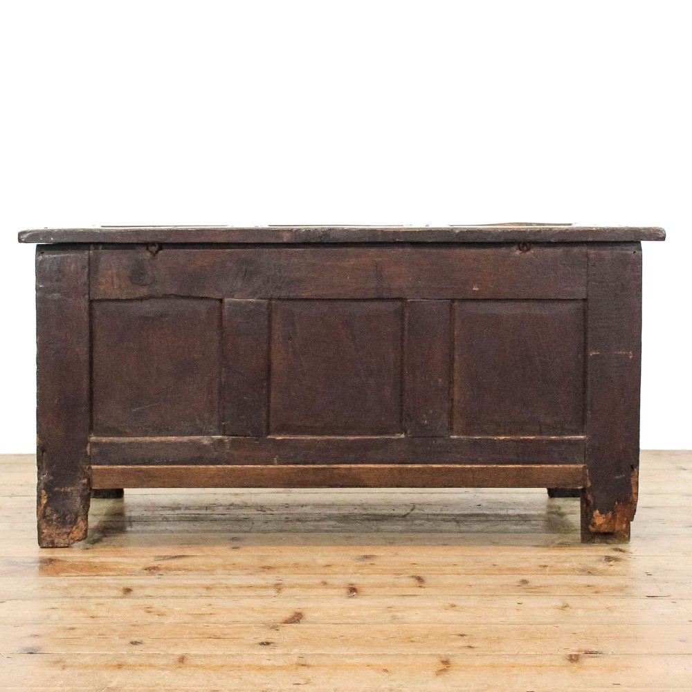 A dark carved oak coffer featuring three front panels, geometric inlay along the frame, arcaded frieze carvings, and a central iron keyhole plate. View V