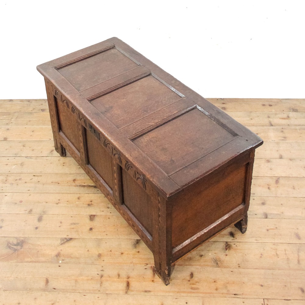 A dark carved oak coffer featuring three front panels, geometric inlay along the frame, arcaded frieze carvings, and a central iron keyhole plate. View VII