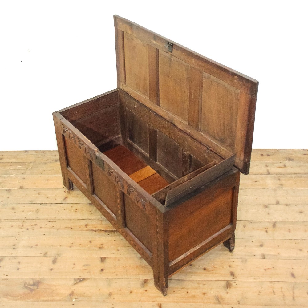 A dark carved oak coffer featuring three front panels, geometric inlay along the frame, arcaded frieze carvings, and a central iron keyhole plate. View VIII