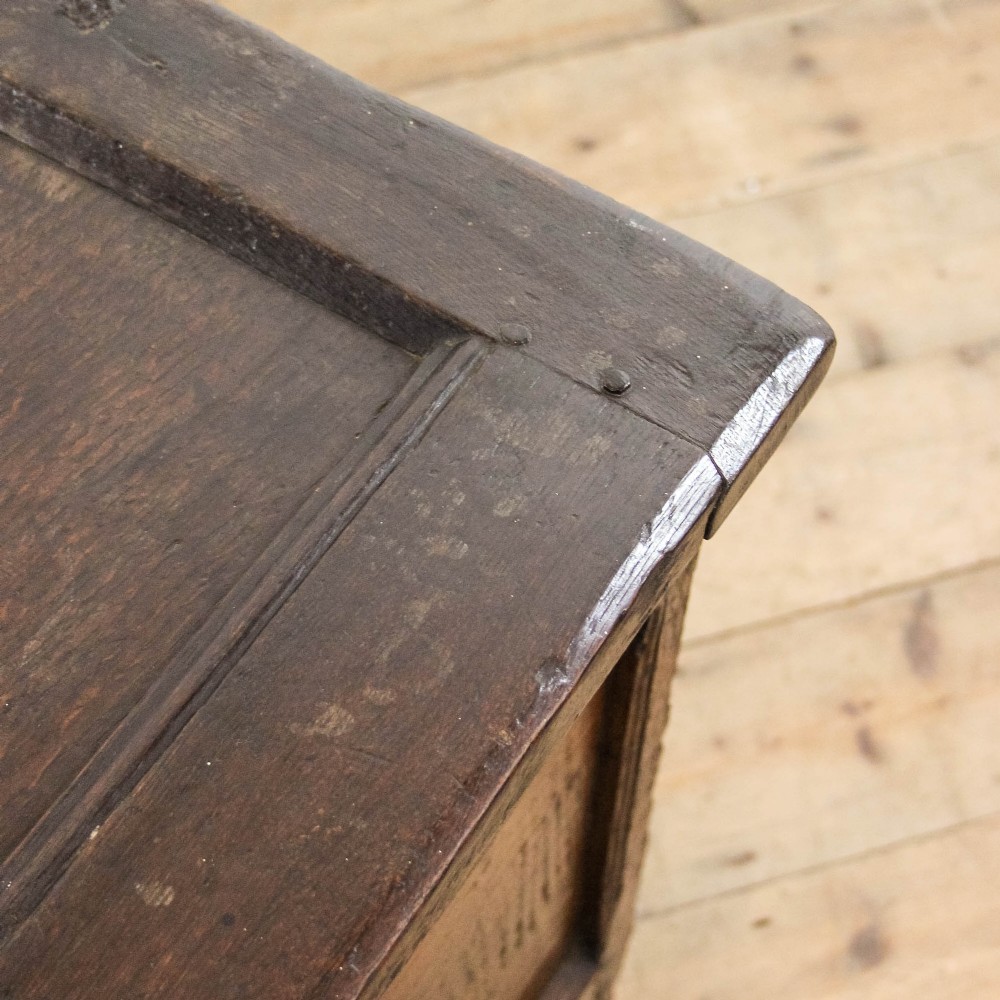 A dark carved oak coffer featuring three front panels, geometric inlay along the frame, arcaded frieze carvings, and a central iron keyhole plate. View XII