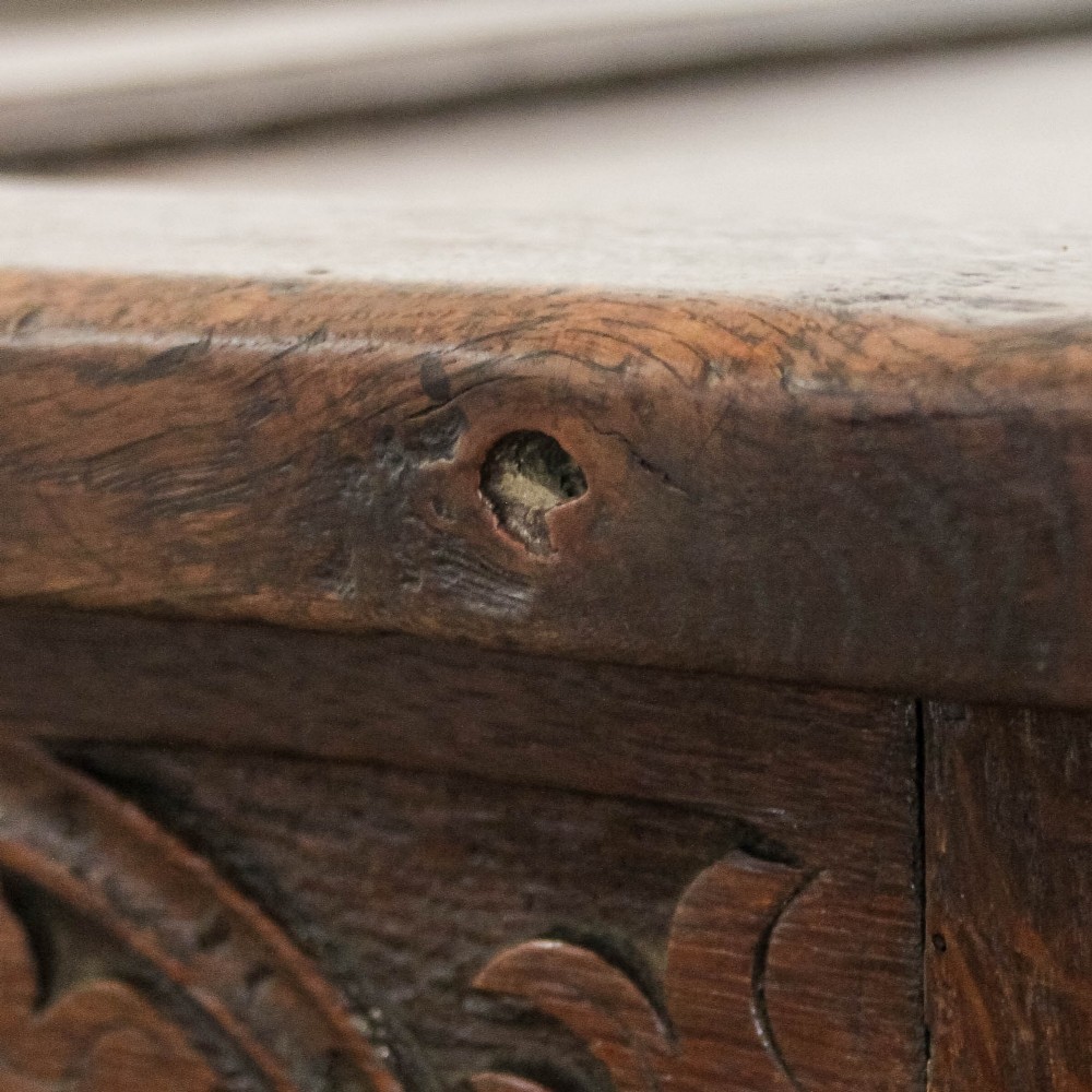 A dark carved oak coffer featuring three front panels, geometric inlay along the frame, arcaded frieze carvings, and a central iron keyhole plate. View XIV