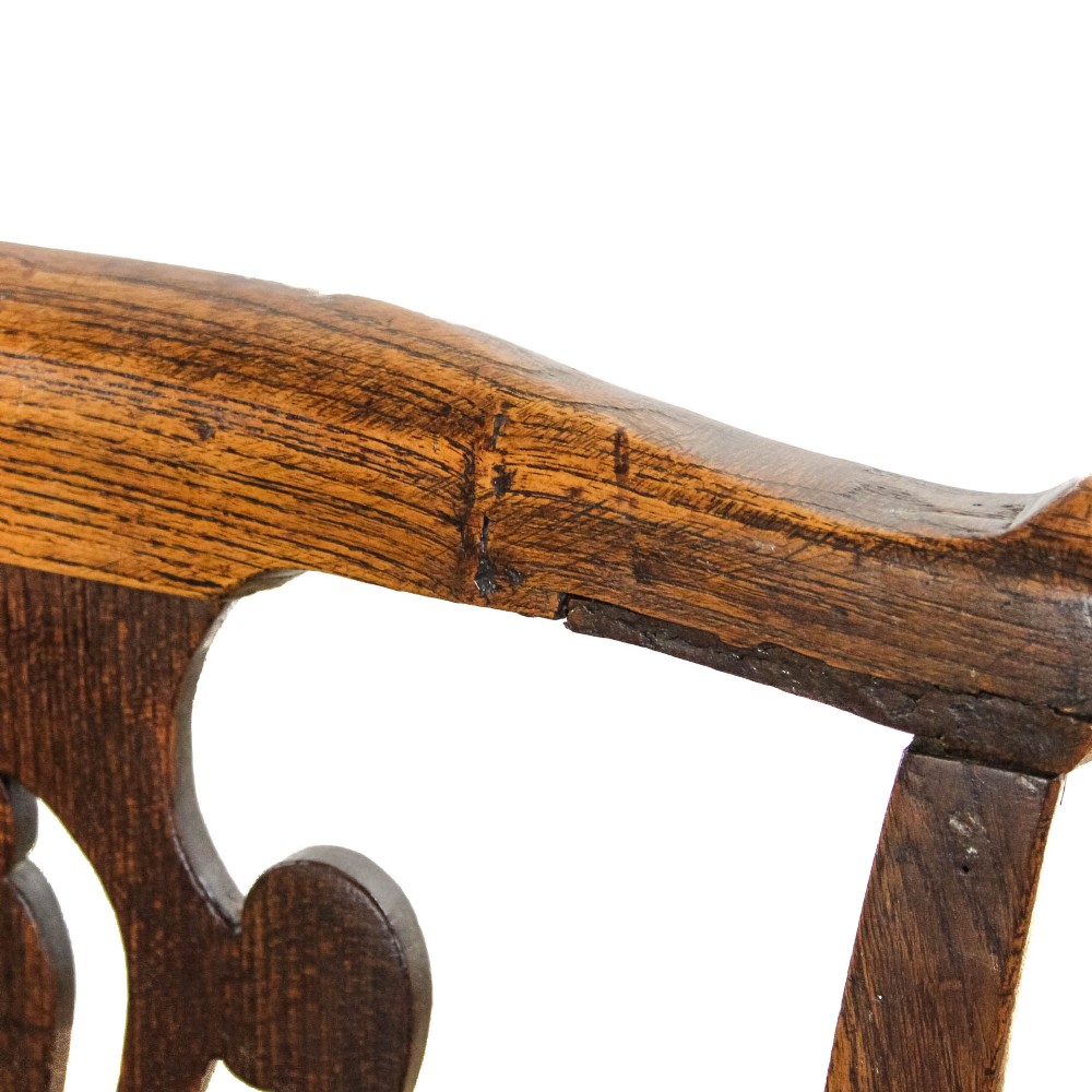 A George III period oak open armchair featuring a pierced vase-shaped back splat, swept arms, a solid wooden seat, and square legs joined by stretchers. View II