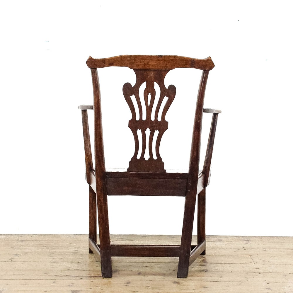 A George III period oak open armchair featuring a pierced vase-shaped back splat, swept arms, a solid wooden seat, and square legs joined by stretchers. View IV
