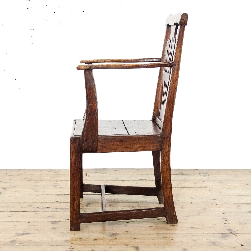 A George III period oak open armchair featuring a pierced vase-shaped back splat, swept arms, a solid wooden seat, and square legs joined by stretchers. View V