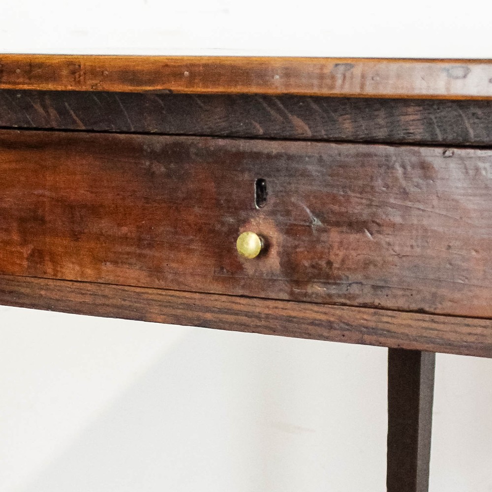 An antique dark oak kitchen table featuring a rectangular top, an end drawer with a brass knob, straight legs, and a low H-stretcher base. View II