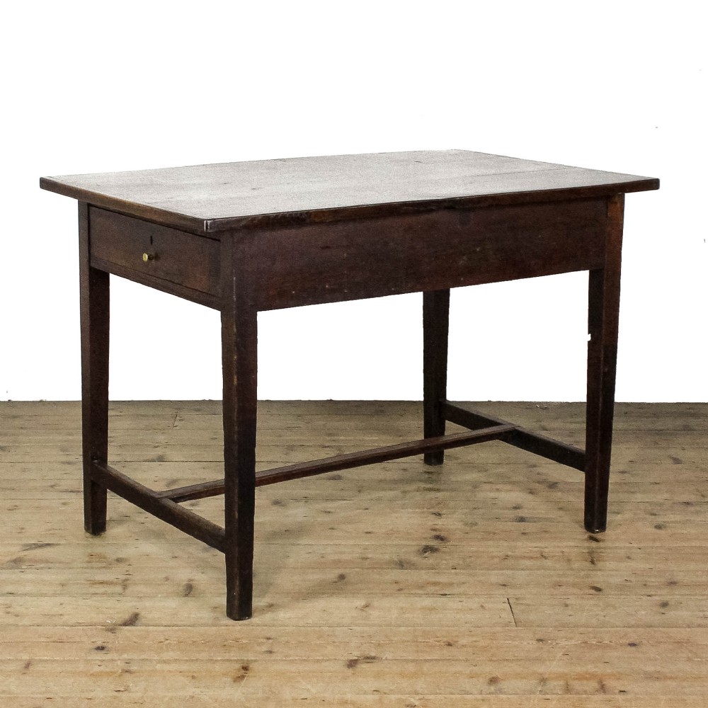 An antique dark oak kitchen table featuring a rectangular top, an end drawer with a brass knob, straight legs, and a low H-stretcher base.