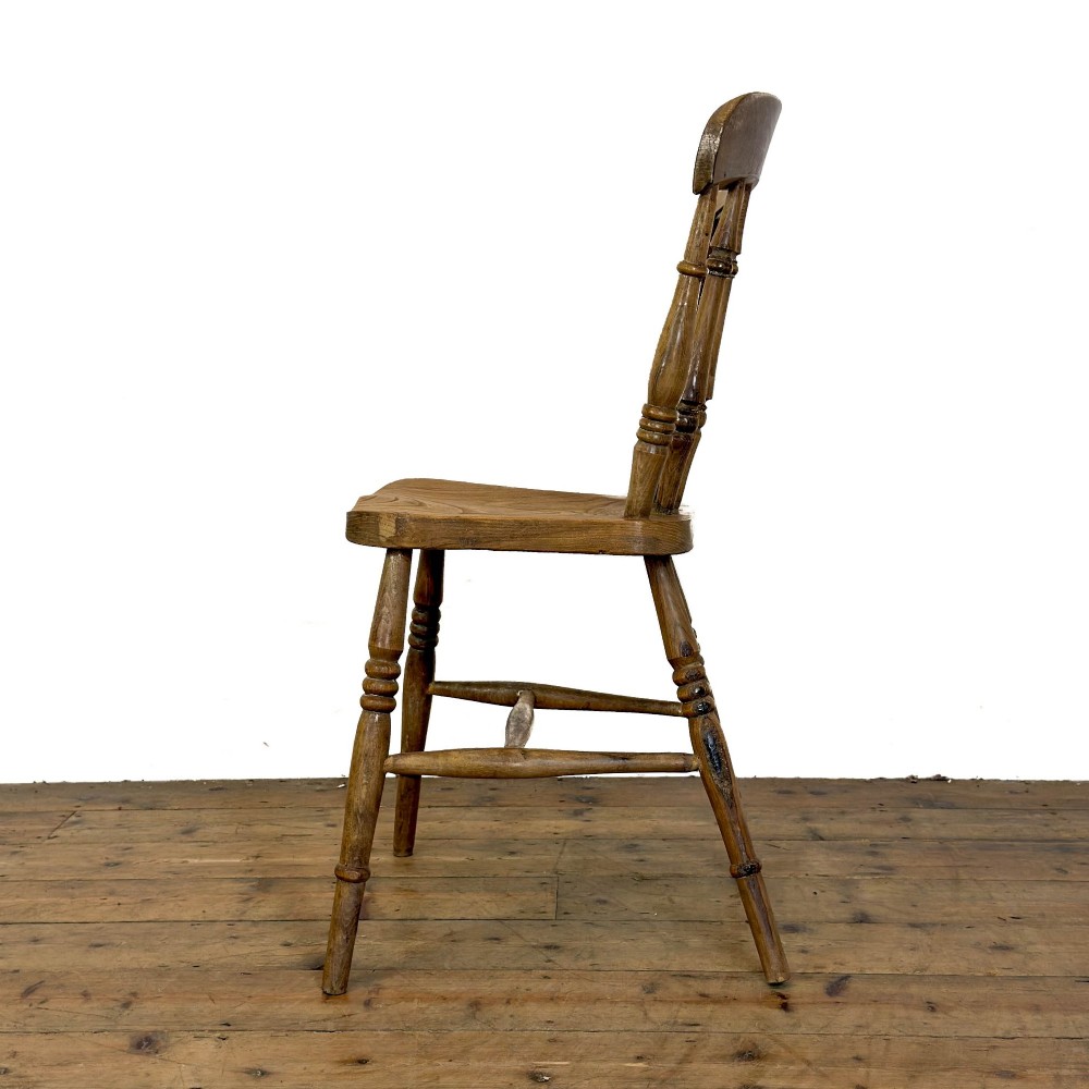 A set of six mismatched vintage wooden dining chairs with turned legs and varied slat and spindle backs arranged together. View V