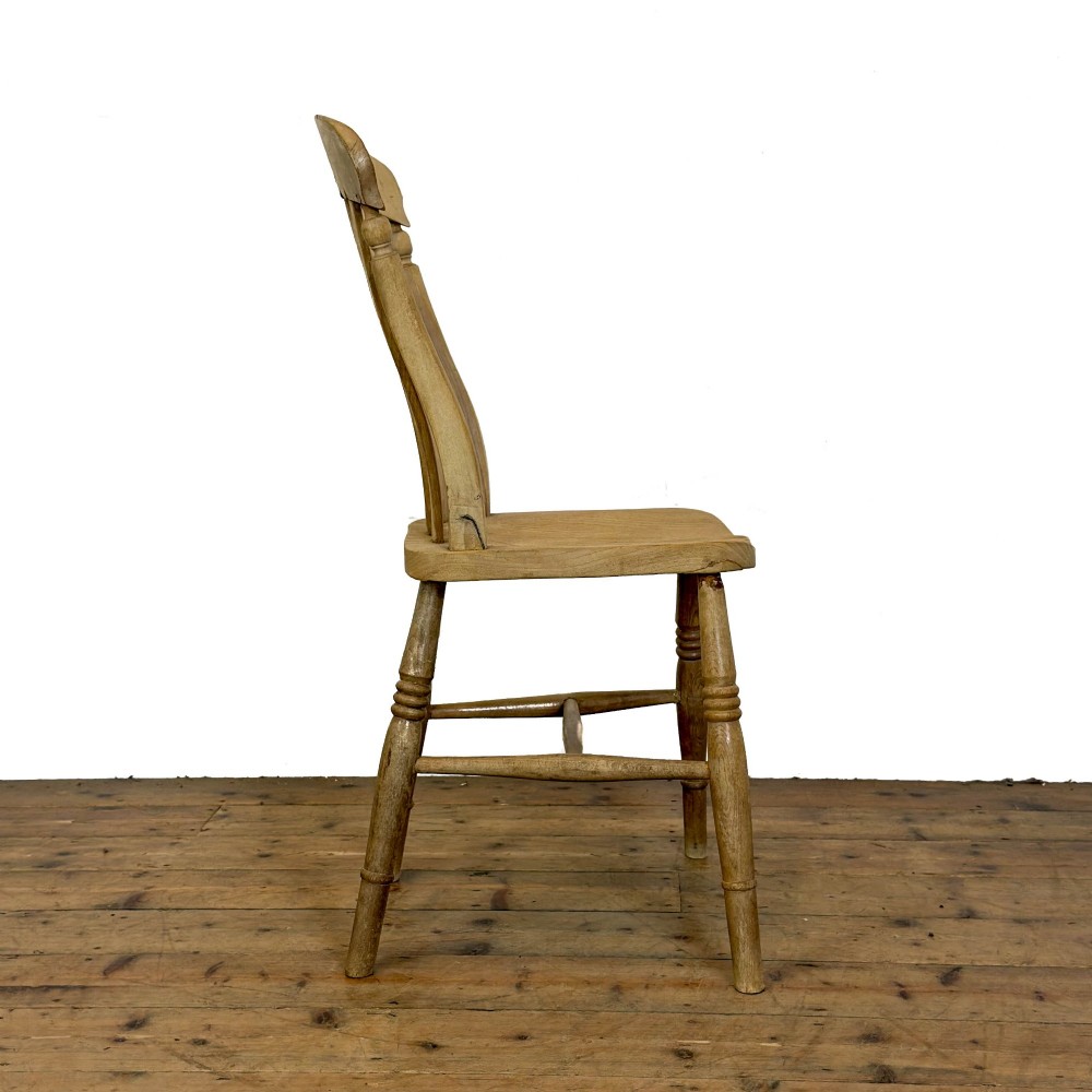A set of six mismatched vintage wooden dining chairs with turned legs and varied slat and spindle backs arranged together. View VI