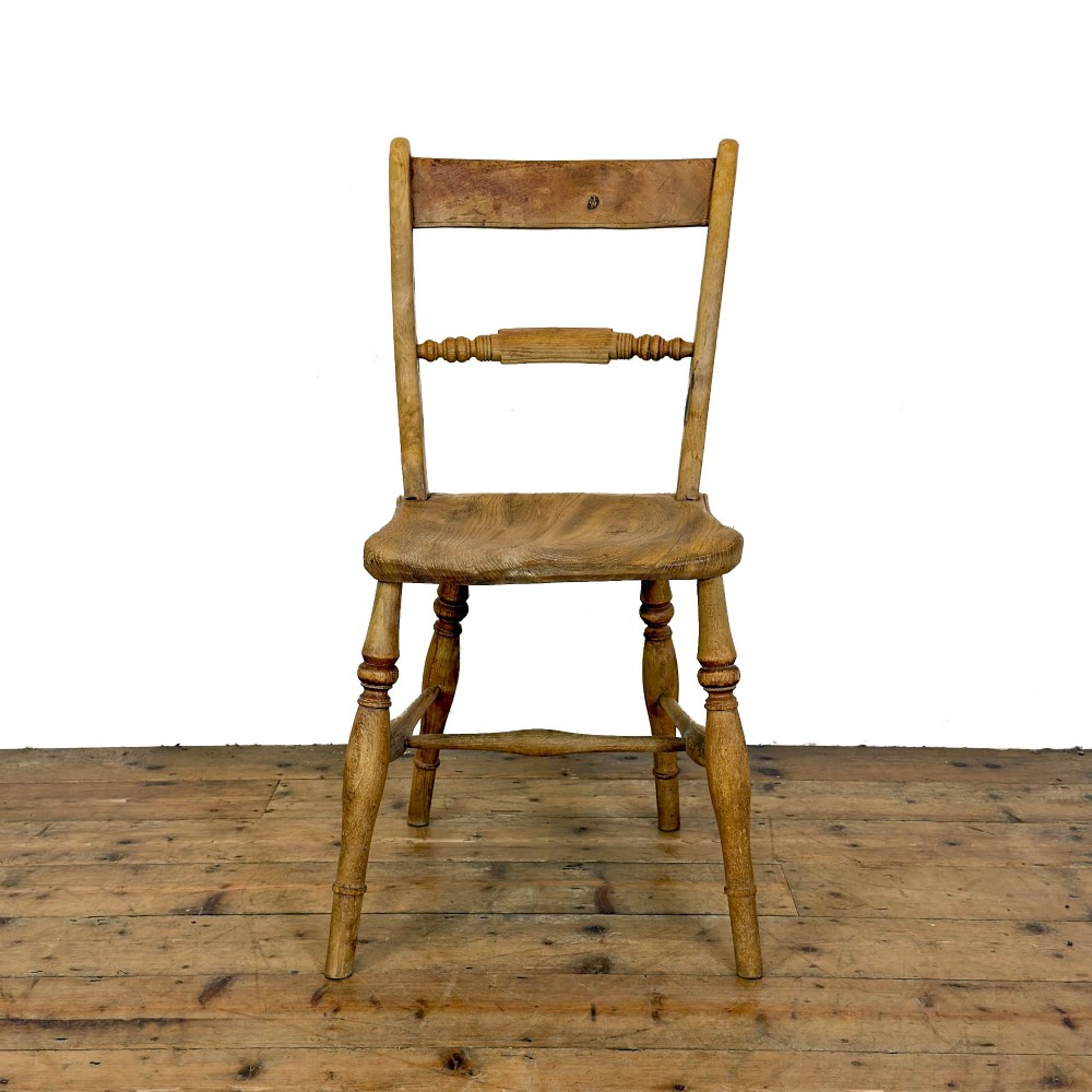 A set of six mismatched vintage wooden dining chairs with turned legs and varied slat and spindle backs arranged together. View VII