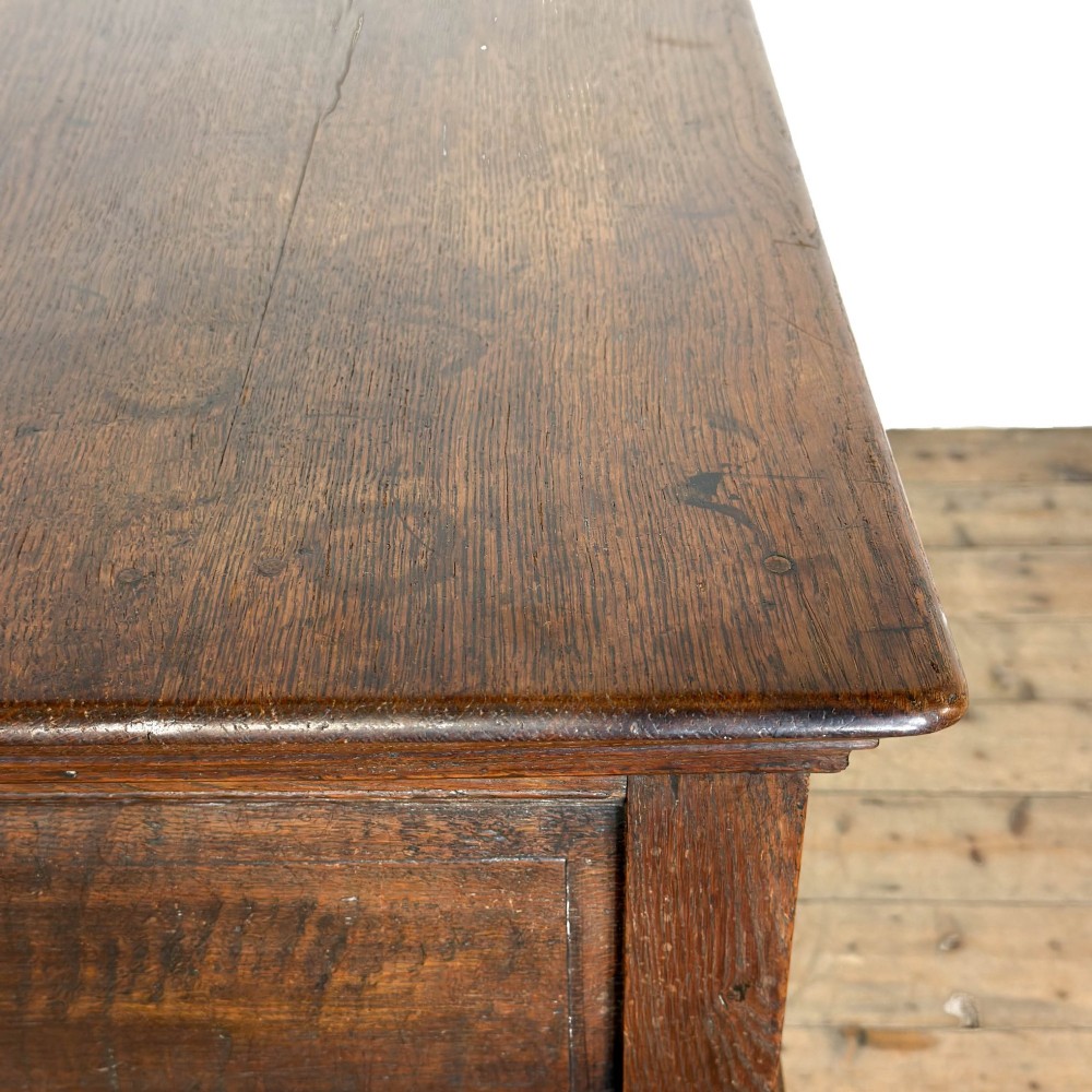 An antique dark oak dresser base featuring two drawers with geometric raised mouldings, brass handles, turned front legs, and a low stretcher. View VI