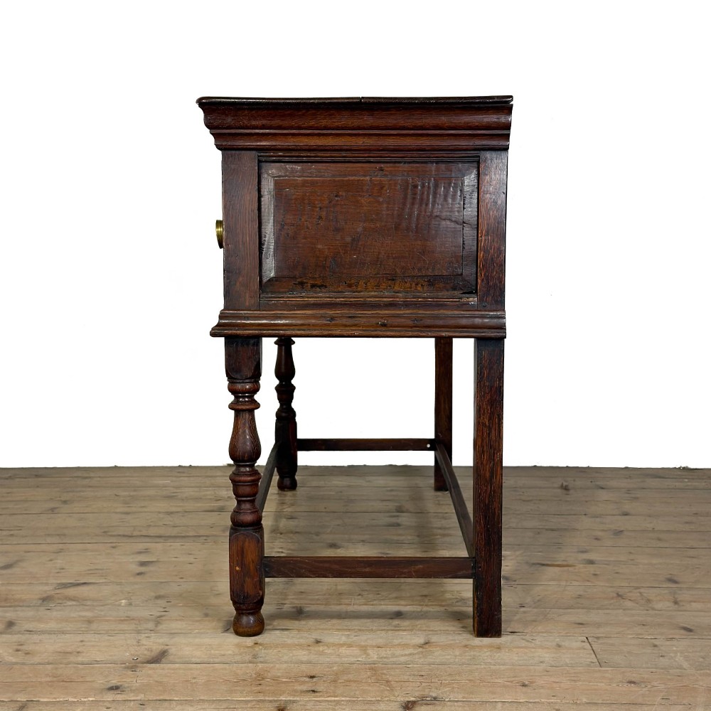 An antique dark oak dresser base featuring two drawers with geometric raised mouldings, brass handles, turned front legs, and a low stretcher. View IX