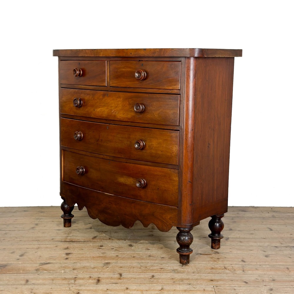 A Victorian mahogany chest of drawers featuring a bowfront profile, two short over three long graduating drawers, turned wooden knobs, and turned feet. View II