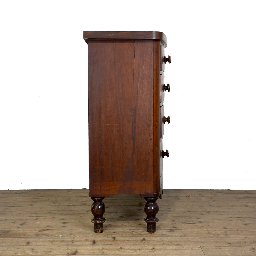 A Victorian mahogany chest of drawers featuring a bowfront profile, two short over three long graduating drawers, turned wooden knobs, and turned feet. View VI