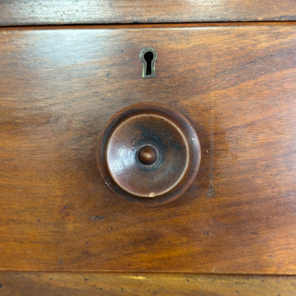A Victorian mahogany chest of drawers featuring a bowfront profile, two short over three long graduating drawers, turned wooden knobs, and turned feet. View IX