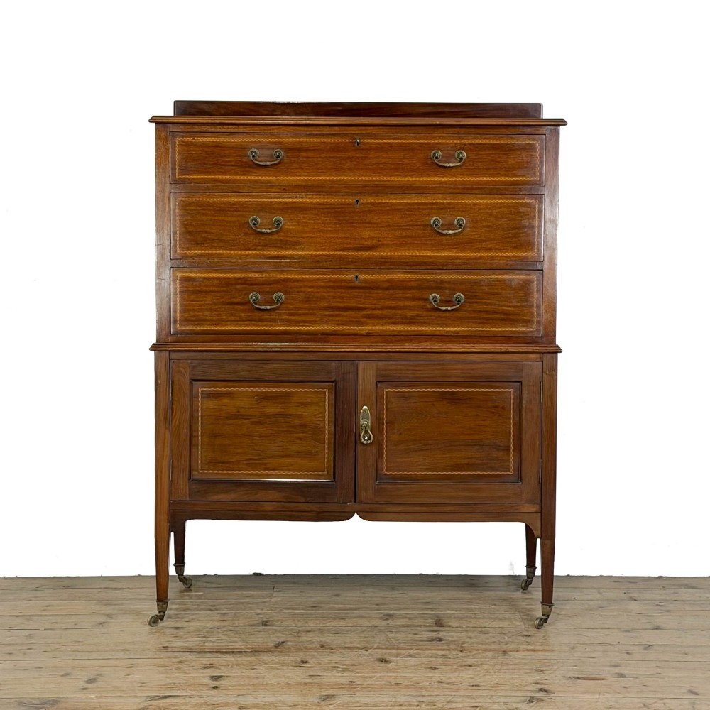 An antique Edwardian mahogany tallboy chest featuring three upper drawers above a double-door cupboard with satinwood string inlay and brass castors.