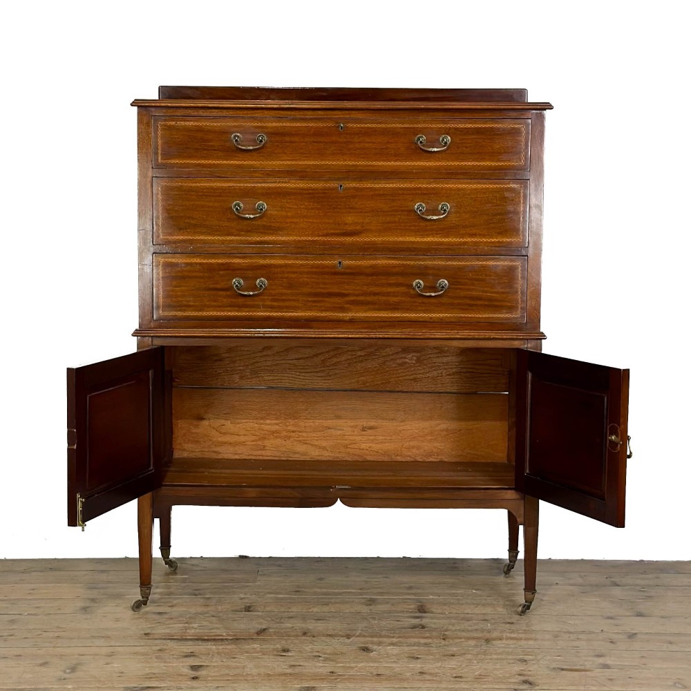 An antique Edwardian mahogany tallboy chest featuring three upper drawers above a double-door cupboard with satinwood string inlay and brass castors. View II