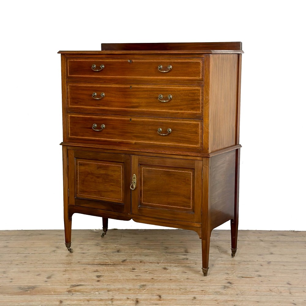 An antique Edwardian mahogany tallboy chest featuring three upper drawers above a double-door cupboard with satinwood string inlay and brass castors. View III