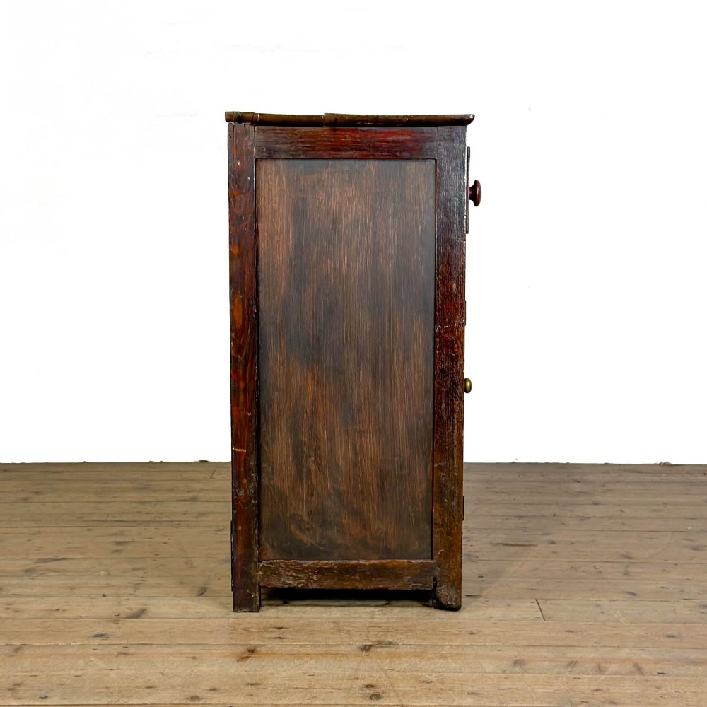 A dark oak antique dresser base featuring three top drawers with wooden knobs and brass keyholes above two panelled cupboards flanking a central open alcove. View XI