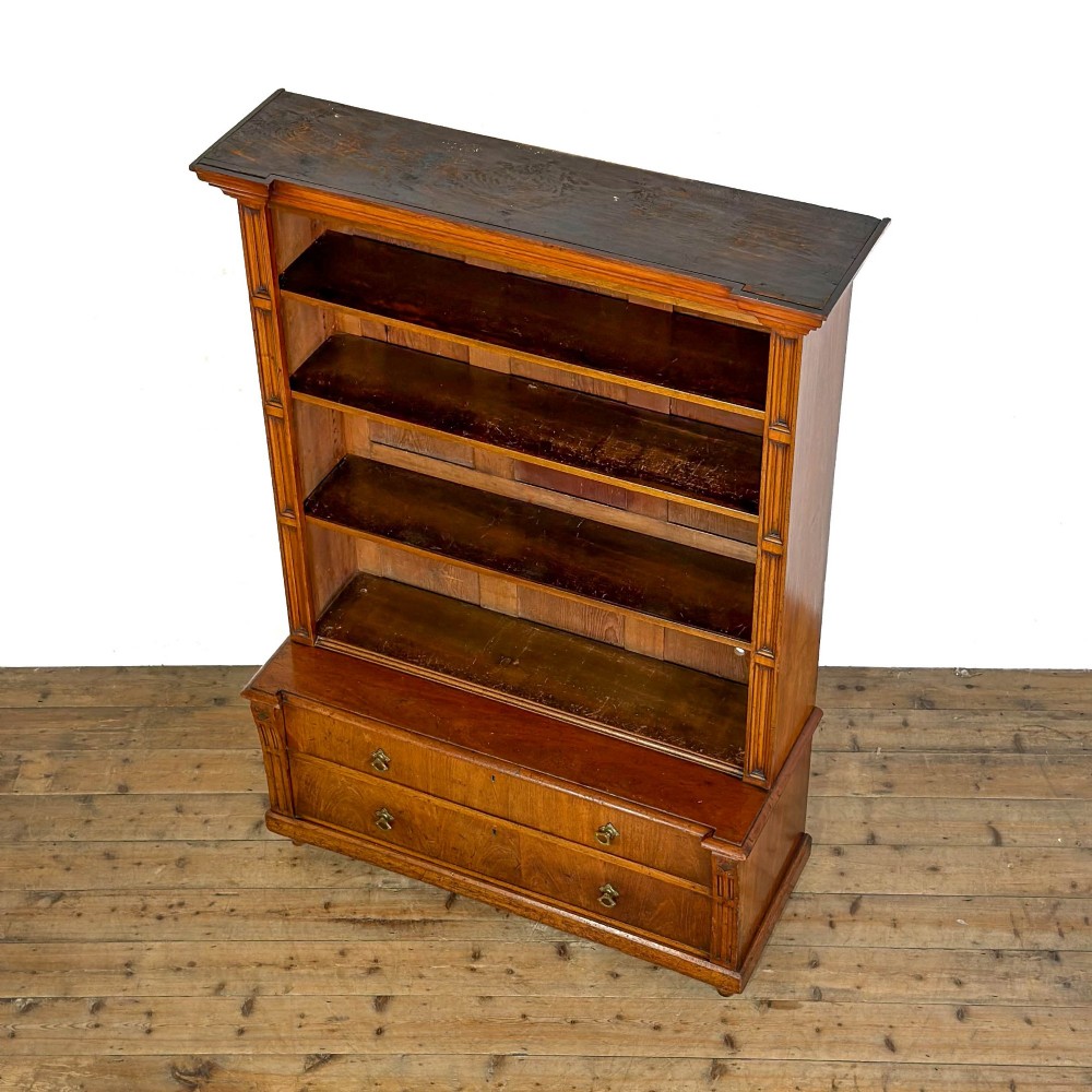 A tall antique open bookcase crafted from warm brown walnut featuring multiple open shelves, fluted side pilasters, and two lower drawers with brass drop handles. View II