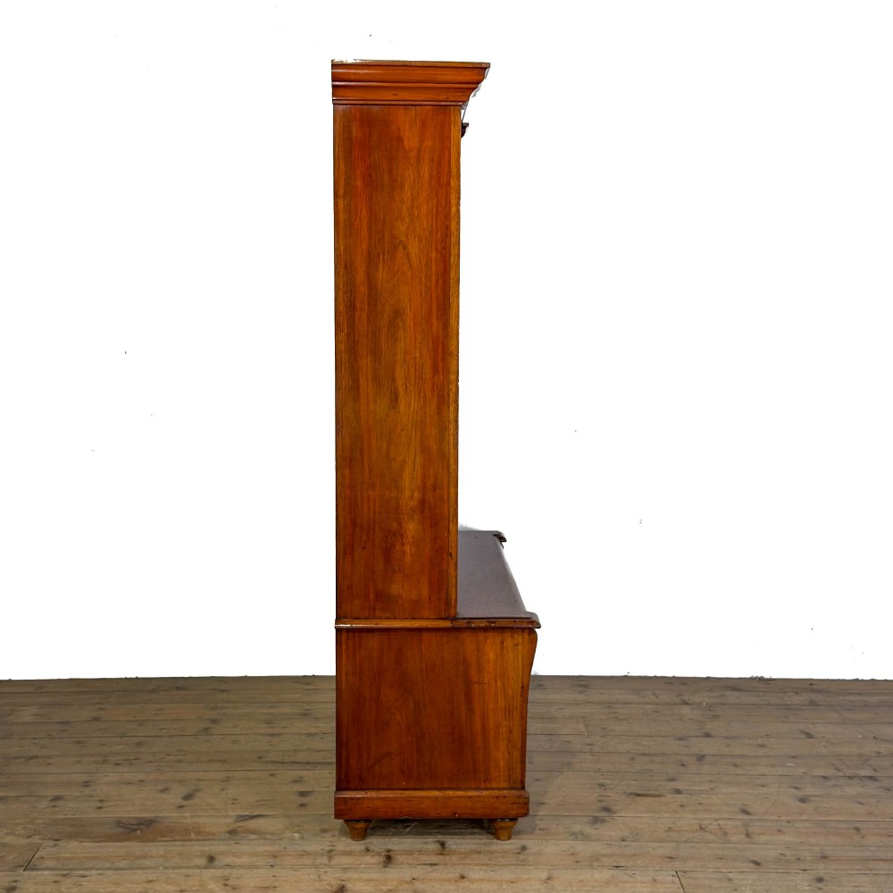 A tall antique open bookcase crafted from warm brown walnut featuring multiple open shelves, fluted side pilasters, and two lower drawers with brass drop handles. View VIII