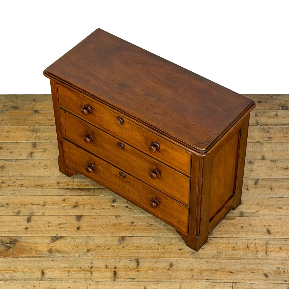 A three-drawer Victorian mahogany chest featuring turned wooden knobs and brass keyhole escutcheons set on a plinth base. View III