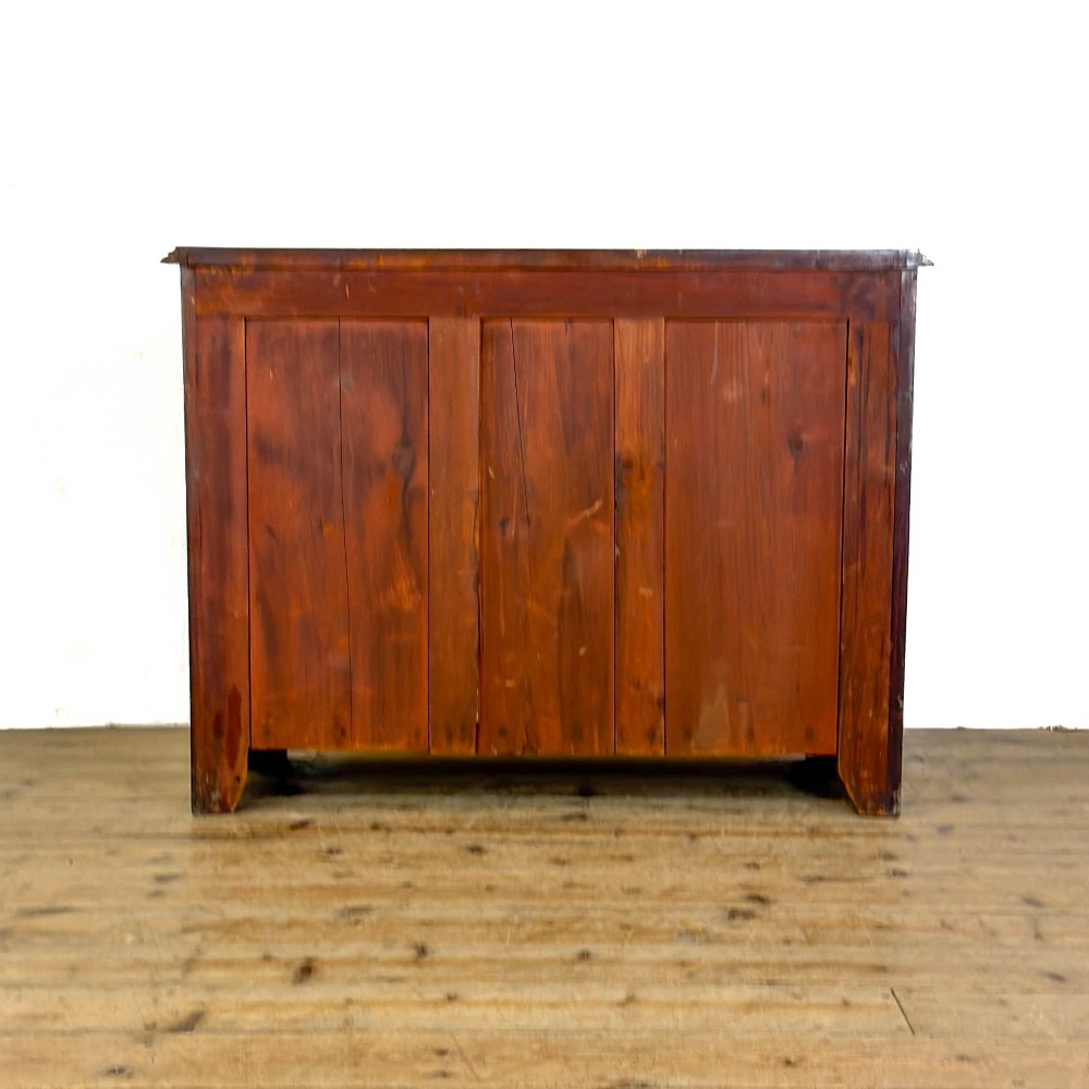 A three-drawer Victorian mahogany chest featuring turned wooden knobs and brass keyhole escutcheons set on a plinth base. View V