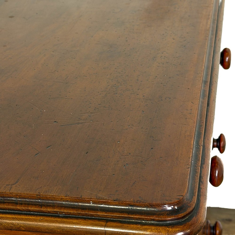 A three-drawer Victorian mahogany chest featuring turned wooden knobs and brass keyhole escutcheons set on a plinth base. View VII
