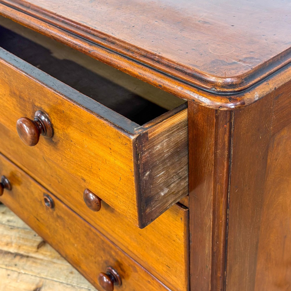 A three-drawer Victorian mahogany chest featuring turned wooden knobs and brass keyhole escutcheons set on a plinth base. View VIII
