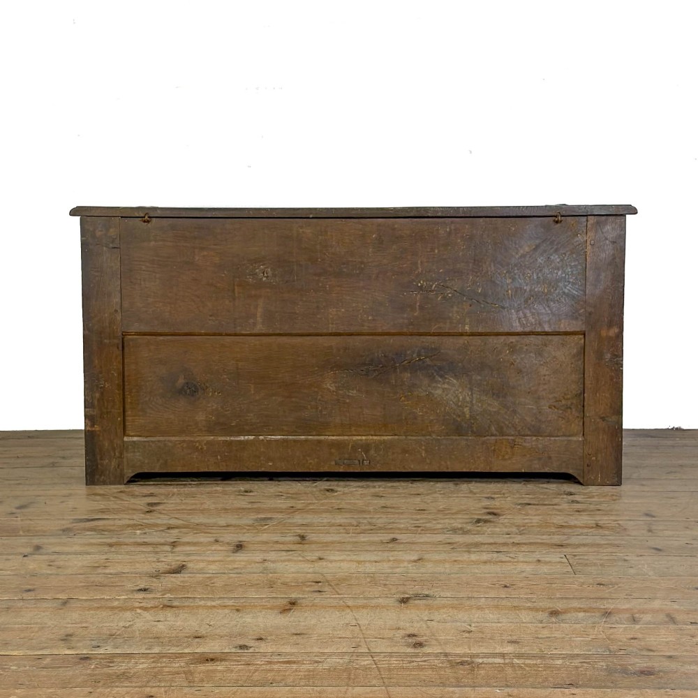A 19th-century warm brown oak coffer featuring three fielded front panels, a brass keyhole escutcheon, and a flat hinged top lid. View IX