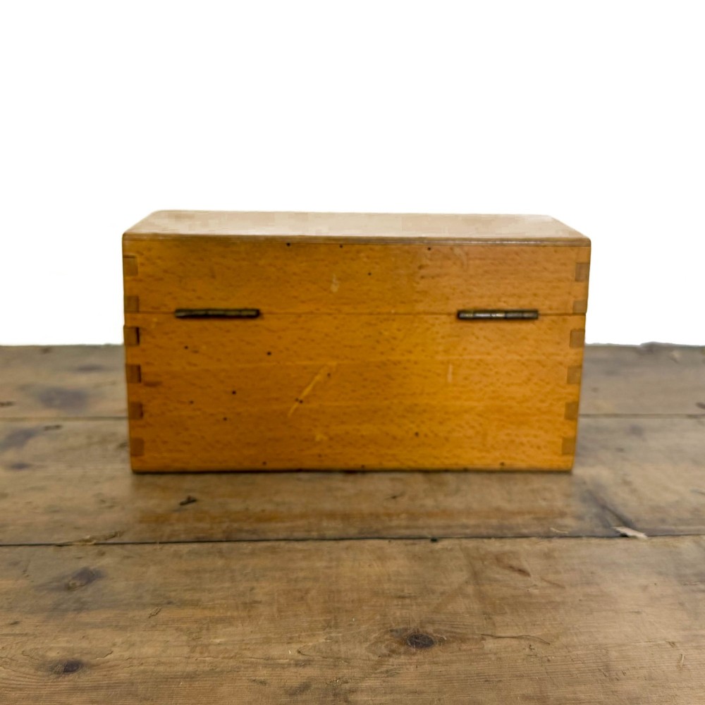 An antique dark oak church hymn board featuring a trefoil cutout at the carved top, painted text reading HYMNS, multiple horizontal slots, and an accompanying wooden box. View VII