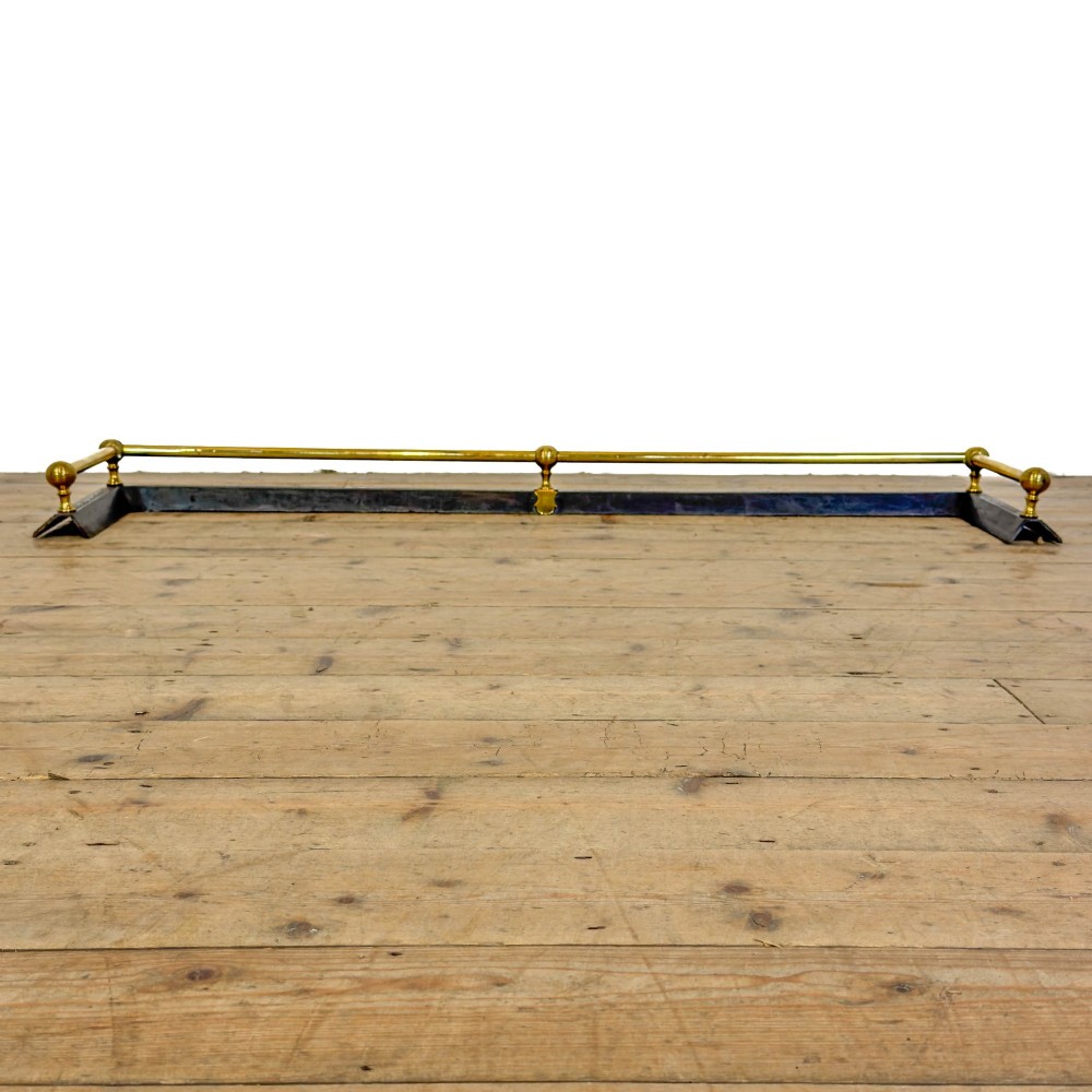 An antique Victorian fireplace fender featuring a dark metal base with stamped geometric patterns and an elevated brass rail supported by ribbed finials. View IV