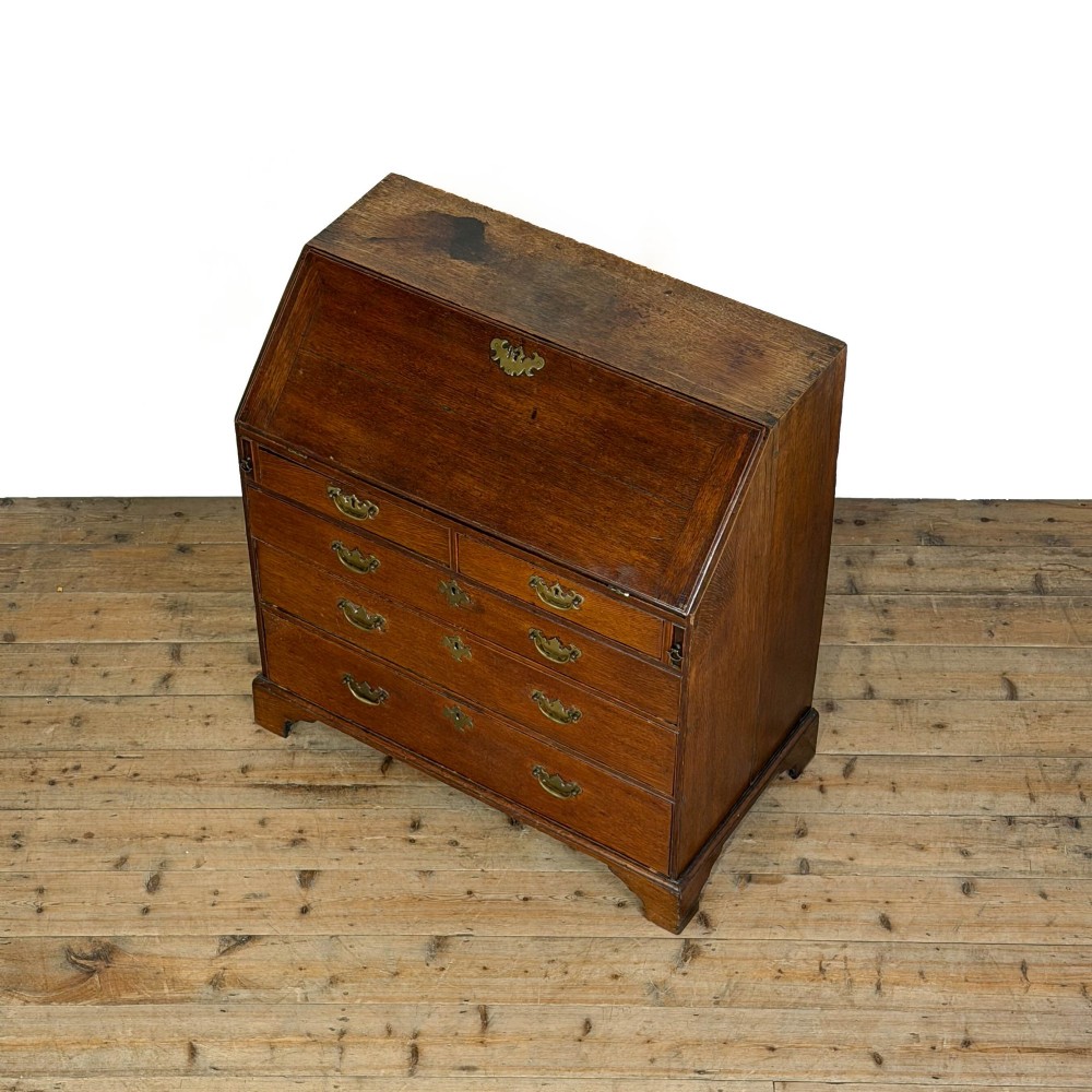 An 18th-century oak writing bureau featuring a sloping fall front above four graduated drawers with brass handles and bracket feet. View IV