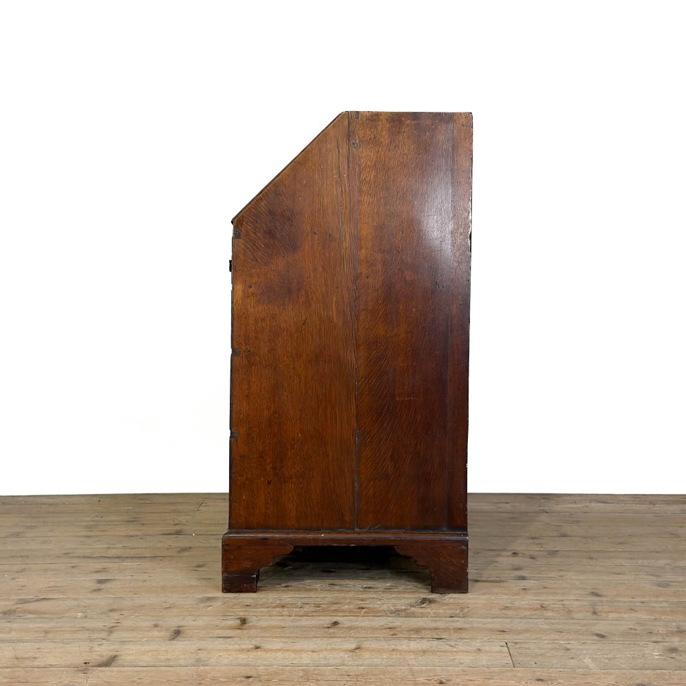 An 18th-century oak writing bureau featuring a sloping fall front above four graduated drawers with brass handles and bracket feet. View VII