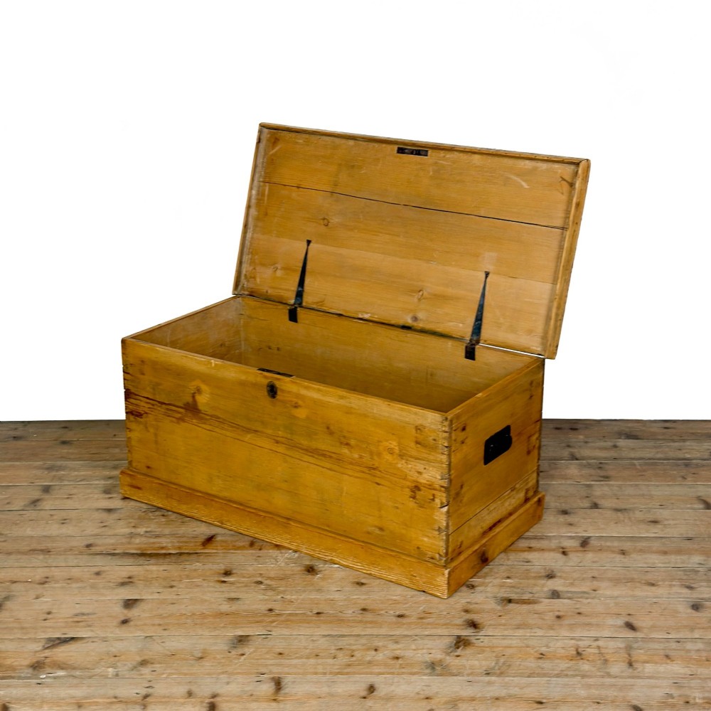 A rectangular stripped pine trunk displaying visible dovetail joints, a brass keyhole escutcheon, and a simple plinth base. View IV