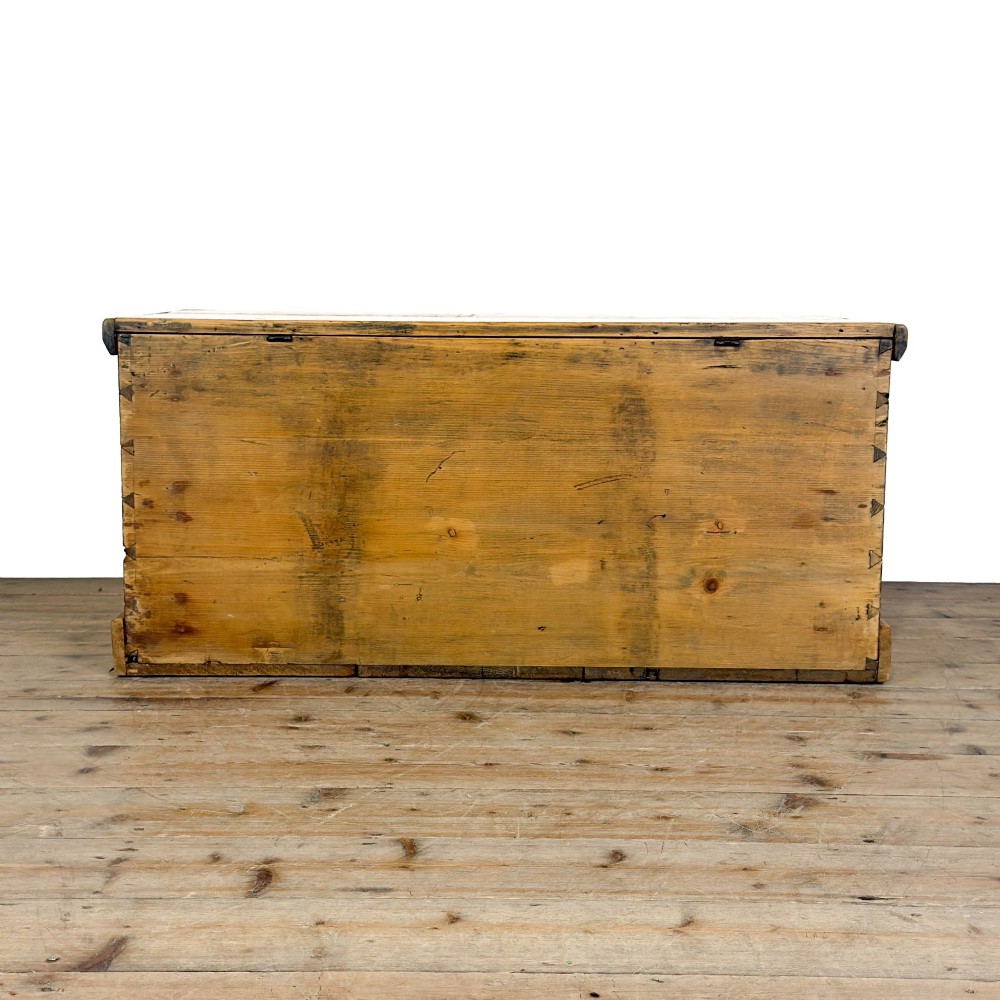A rectangular stripped pine trunk displaying visible dovetail joints, a brass keyhole escutcheon, and a simple plinth base. View VIII