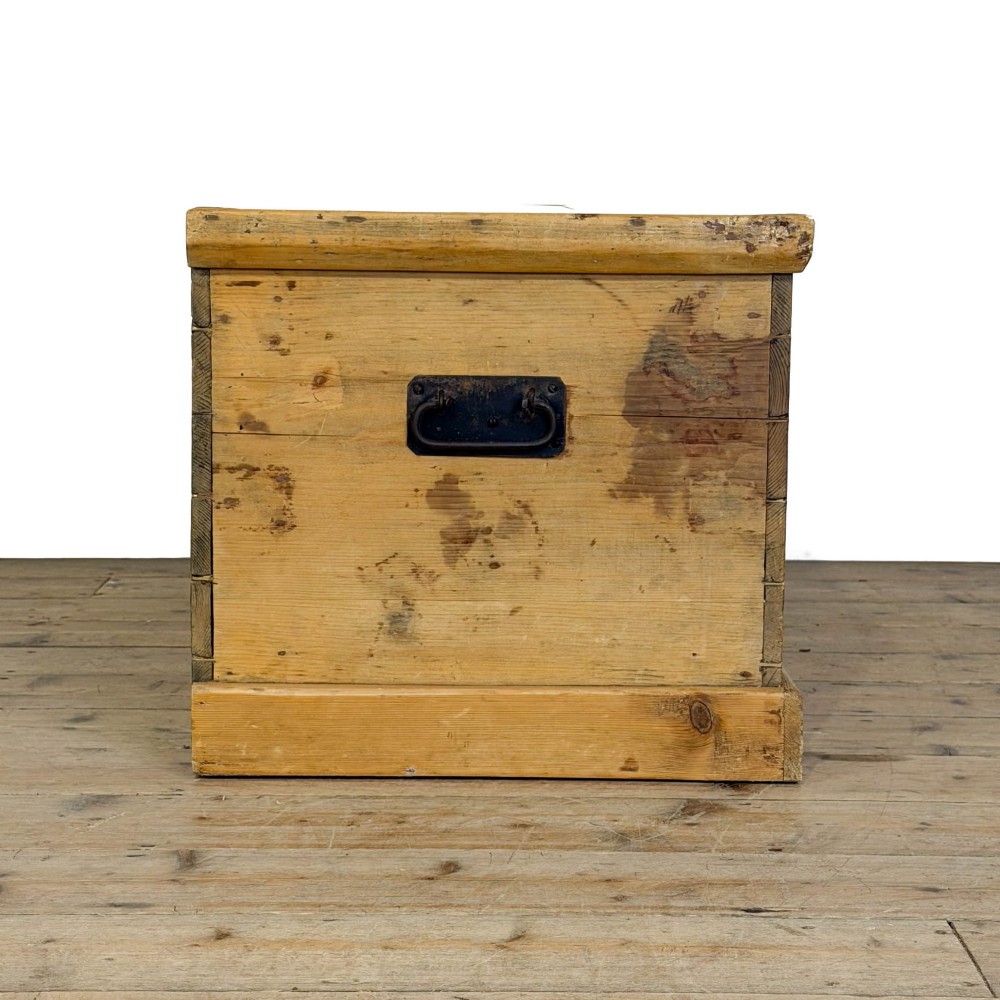 A rectangular stripped pine trunk displaying visible dovetail joints, a brass keyhole escutcheon, and a simple plinth base. View IX