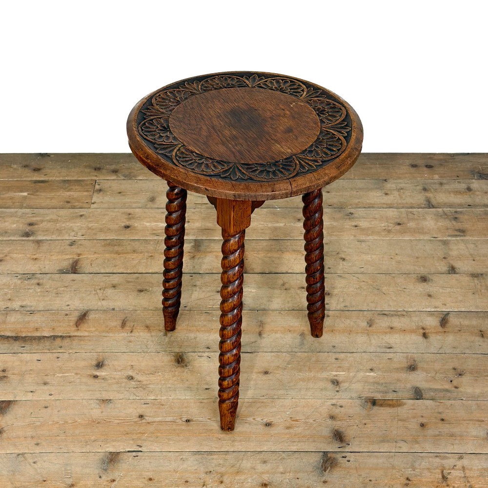 A small circular dark oak cricket table featuring a relief-carved top border and three spiral barley twist tripod legs. View III