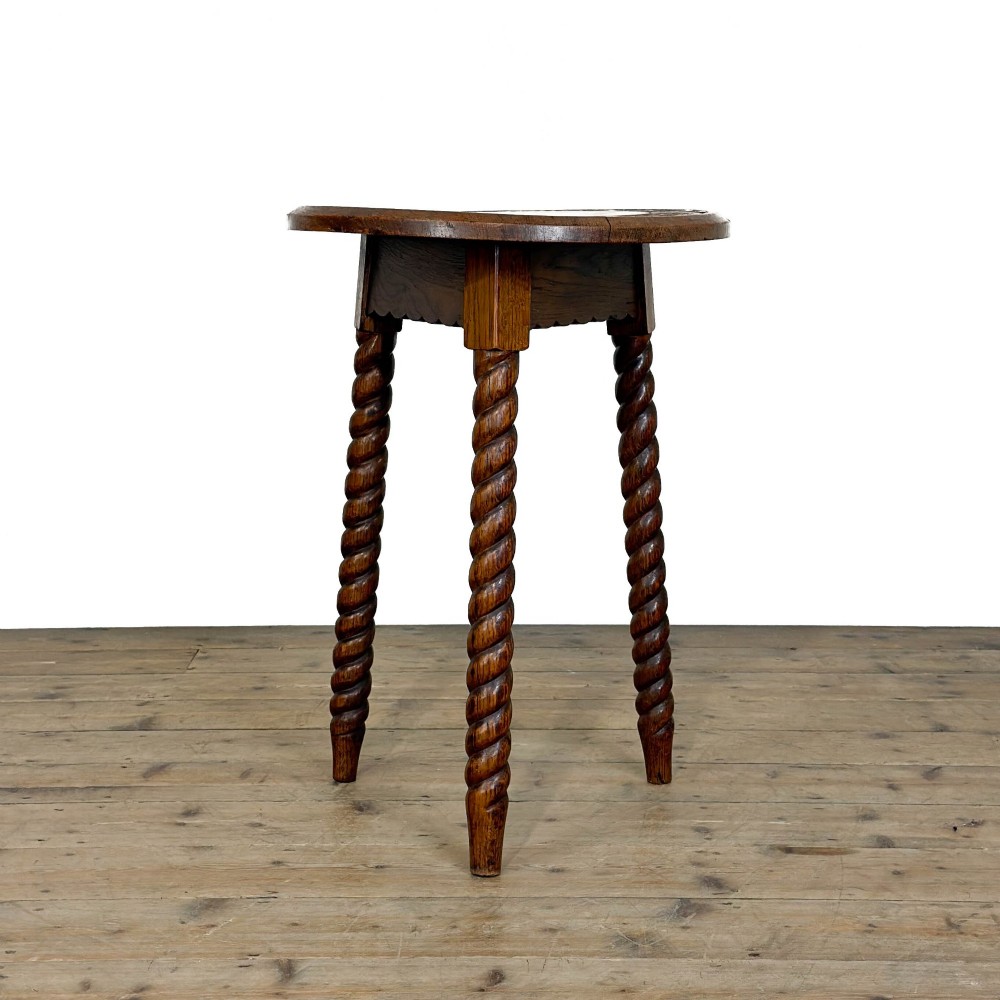 A small circular dark oak cricket table featuring a relief-carved top border and three spiral barley twist tripod legs. View IV