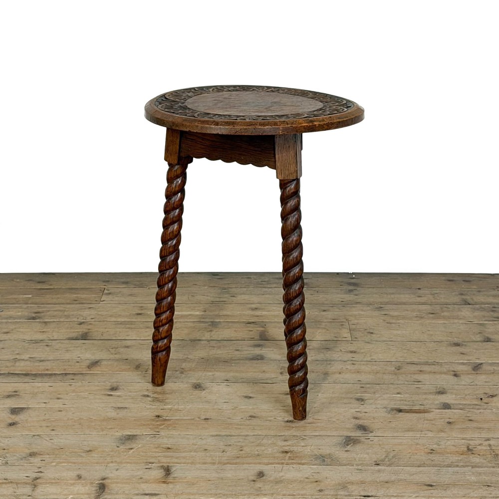 A small circular dark oak cricket table featuring a relief-carved top border and three spiral barley twist tripod legs. View VI