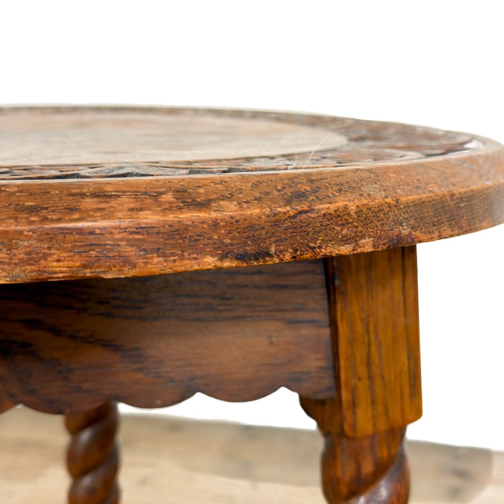 A small circular dark oak cricket table featuring a relief-carved top border and three spiral barley twist tripod legs. View VIII