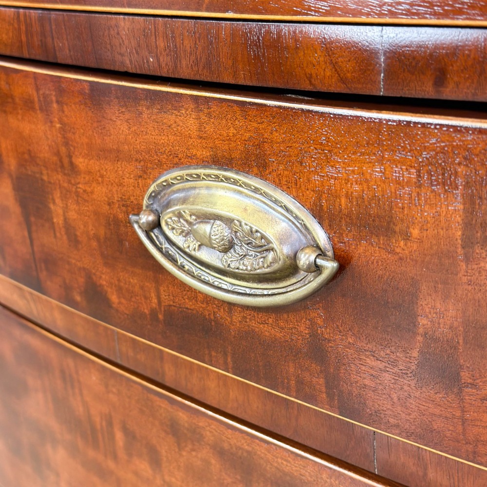 An antique Georgian mahogany bow-front chest of drawers with four graduated drawers and brass oval drop handles. View IX