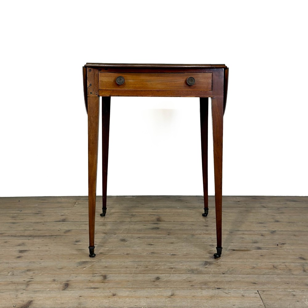 A 19th-century mahogany Pembroke table featuring two curved drop leaves, a single drawer with round brass knobs, and four square tapered legs on castors. View IX