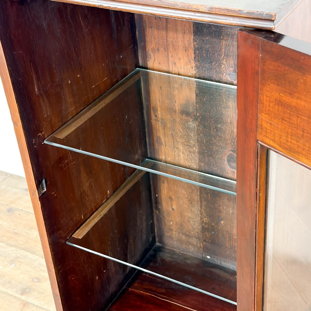 An antique dark wood Art Nouveau display cabinet featuring floral marquetry inlays, a single glazed glass door, and a shaped cresting gallery. View V